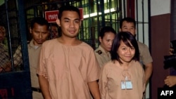 Thai student Patiwat Saraiyaem, 23, left, and activist Porntip Mankong, 26, are escorted by prison security guards after their verdict at the Criminal Court in Bangkok, Feb. 23, 2015. 