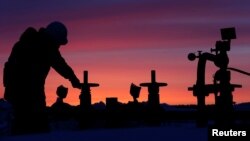 FILE - A worker checks the valve of an oil pipe at an oil field owned by Russian state-owned oil producer Bashneft near the village of Nikolo-Berezovka, northwest of Ufa, Bashkortostan, Russia, Jan. 28, 2015. 