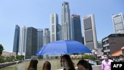 戴着口罩的人们走过新加坡金融区附近的一座桥。（2021年4月20日）