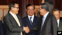 Cambodian Prime Minister Hun Sen, second from right, shakes hands with the main opposition party leader Sam Rainsy, left, of Cambodia National Rescue Party, as Deputy Prime Minister Sar Kheng, second from left, looks on after a meeting in Senate headquarters, Phnom Penh, Cambodia, July 22, 2017)
