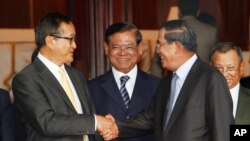 រូបឯកសារ៖ លោកនាយករដ្ឋមន្ត្រី ហ៊ុន សែន ចាប់ដៃគ្នាជាមួយលោក សម រង្ស៊ី អតីតប្រធានគណបក្សសង្គ្រោះជាតិដែលត្រូវបានតុលាការរំលាយ ស្របពេលលោកឧបនាយករដ្ឋមន្ត្រី ស ខេង ឈរកណ្តាល នៅមុខព្រឹទ្ធសភាជាតិ បន្ទាប់ពីកិច្ចប្រជុំមួយ​ កាលពីថ្ងៃទី២២ ខែកក្កដា ឆ្នាំ២០១២។ 