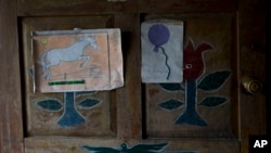 FILE - Artwork by Felipe Gomez Alonzo, an 8-year-old Guatemalan boy who died in U.S. custody, is taped to a door of the Gomez home in Yalambojoch, Guatemala, Dec. 29, 2018. U.S. officials said a Guatemalan teen died April 30, 2019, in a Texas hospital while in U.S. custody. 