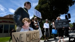 FILE - This April 28, 2019, file photo shows Kyle Fox holding a sign with his father Brady Fox in support of the victims of Chabad of Poway synagogue shooting in Poway, Calif. 