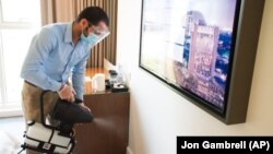 In this Monday, July 6, 2020 photograph, an employee wearing a mask due to the coronavirus pandemic fogs disinfectant in a hotel room at the Rove City Centre Hotel in Dubai, United Arab Emirates. 