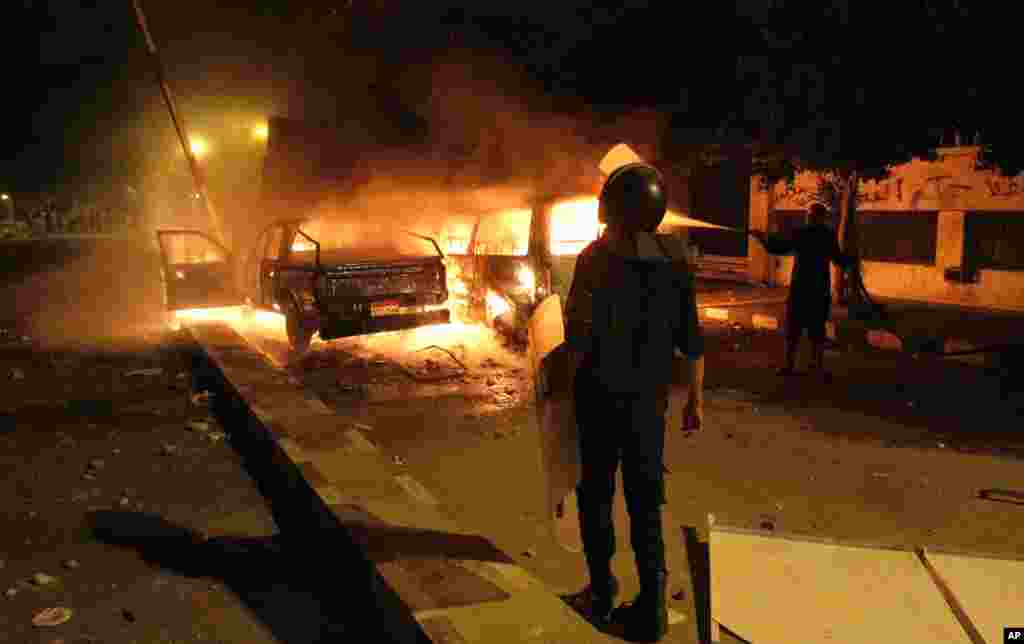 A policeman stands in front of a police car set on fire by protesters in front of the U.S. embassy in Cairo, Egypt, during clashes between protesters and police, September 13, 2012.