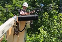 FILE - A technician works on a line used to provide broadband internet service in a rural area in Stowe, Vermont, July 29, 2020.