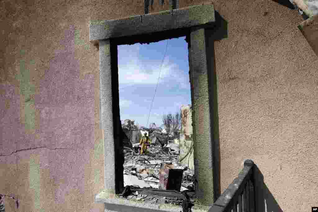 Firefighter Philip Pinal, of Cal-Fire Lions Valley, searches for burning embers in a devastated home after a wildfire in Carlsbad, California, May 16, 2014.