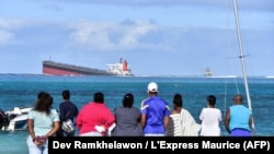 Des spectateurs regardent le vraquier Wakashio qui s'est échoué et dont le pétrole fuit près du parc marin de Blue Bay, dans le sud-est de l'île Maurice, le 6 août 2020. (Photo by Dev Ramkhelawon / L'Express Maurice / AFP)