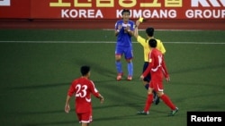 A player from the Philippines receives a yellow card while playing against North Korea. Researchers are studying what makes a soccer official "elite."