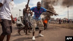 Demonstrators gather in front of a burning car during an opposition rally in Kinshasa, DRC, Sept. 19, 2016.