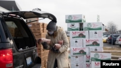 A woman holds goods as Forgotten Harvest food bank distributes goods ahead of Christmas, amid the coronavirus disease (COVID-19) pandemic in Warren, Michigan, Dec. 21, 2020. 
