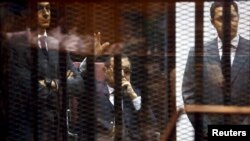 Mantan presiden Mesir Hosni Mubarak dan dua putranya Gamal (kiri) and Alaa di dalam sel di ruangan sidang di pinggir kota Kairo (9/5). (Reuters/Amr Abdallah Dalsh)