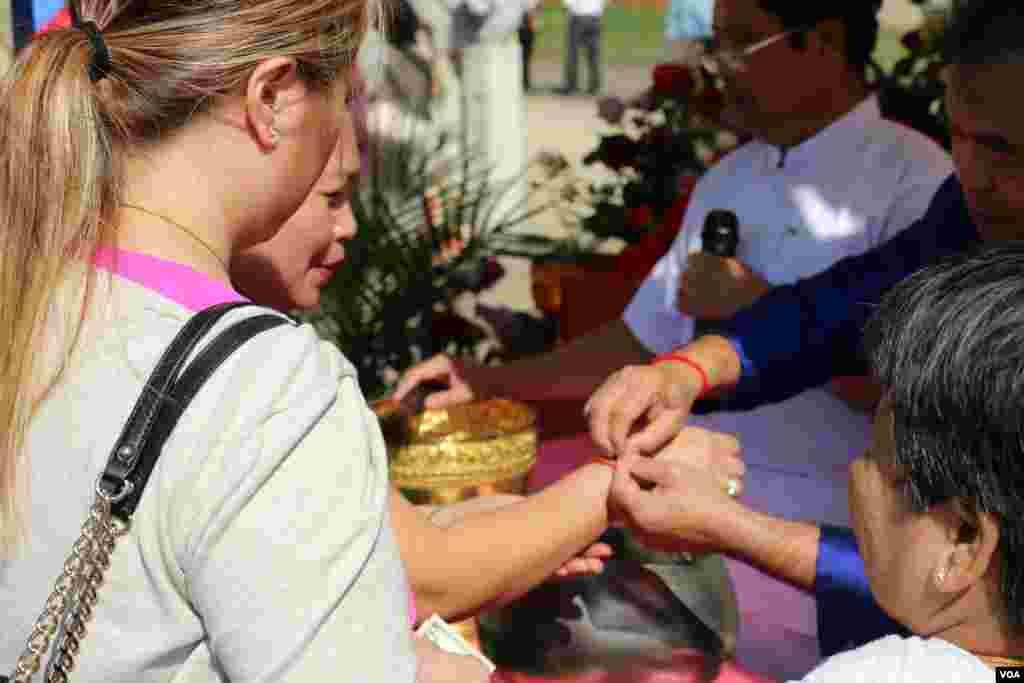 អ្នក​កាន់​ពុទ្ធសាសនា​ចង​ខ្សែ​អំបោះ​ដើម្បី​ទទួល​សិរីសួស្ដី។ (ចាប ចិត្រា/VOA)