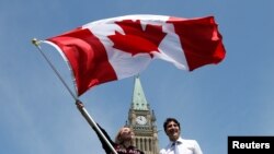 Une sportive canadienne tient le drapeau national près du Premier ministre Justin Trudeau au Parliament Hill à Ottawa, Ontario, Canada, le 21 juillet 2016.