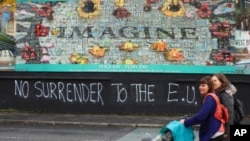 Pejalan kali berjalan melewati grafiti pro-Brexit di West Belfast, Irlandia Utara, 14 Oktober 2019. 
