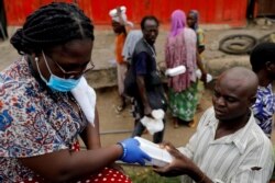 A volunteer distributes cooked food and water to the underprivileged and homeless in Accra, as Ghana enforces a partial lockdown in Accra and Kumasi in efforts to slow the spread of the coronavirus disease (COVID-19), April 4, 2020.