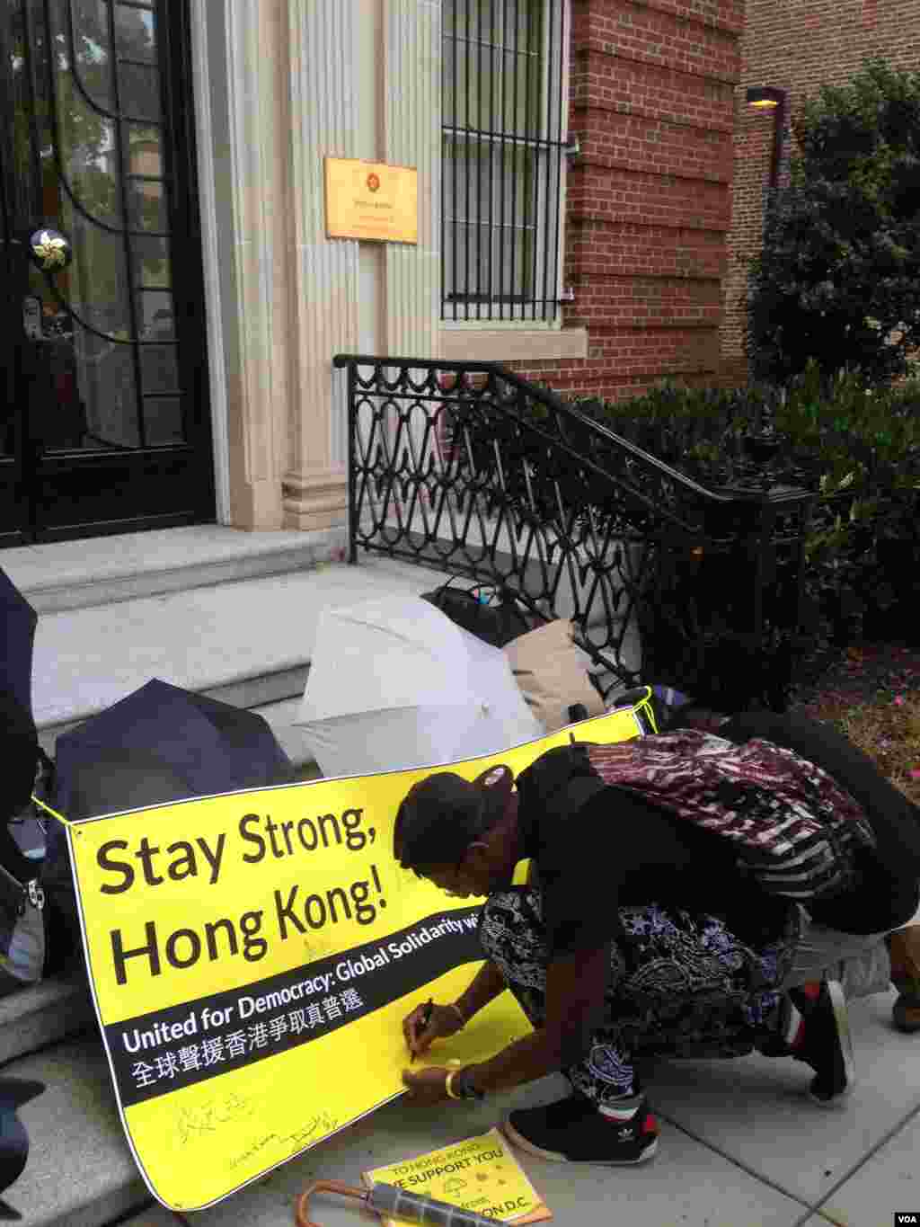 Supporters of Hong Kong&rsquo;s pro-democracy movement sign a banner outside the Hong Kong Economic &amp; Trade Office in Washington, Oct. 1, 2014. (Michael Lipin/VOA) 