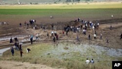 People watch the Thursday's explosion site in Sarikamis district outside Diyarbakir, Turkey, Friday, May 13, 2016.