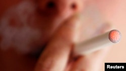 A woman smokes an e-cigarette, an electronic substitute of a normal cigarette, in Bordeaux, southwestern France.