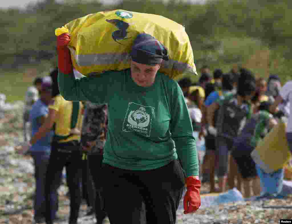 Rebecca Lawson dari Pennsylvania, AS, seorang misionaris dari lembaga Stewards of Creation, bergabung dengan aktivis lingkungan, pekerja sukarela dan murid sekolah dalam membersihkan sampah di pantai Paranaque, Manila, Filipina. (Reuters/Romeo Ranoco)
