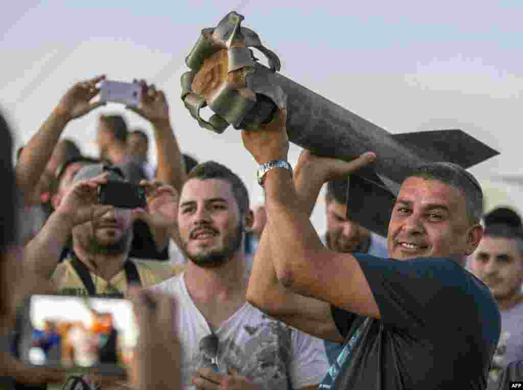 Israeli residents, mostly from the southern Israeli city of Sderot, show the remains of a rocket, on July 13, 2014. So far, no Israelis have been killed in the latest round of violence.