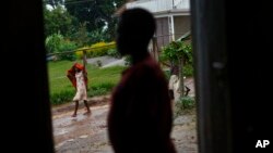 A pregnant 15-year-old girl who was the victim of statutory rape, stands in a doorway of the house where she stays in Masaka, Uganda, May 30, 2017. She is having difficulty pressing charges against the perpetrator because she cannot prove that she is under 18.