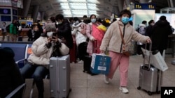 北京南站戴着口罩的旅客在候车室里等待。（2022年1月14日）