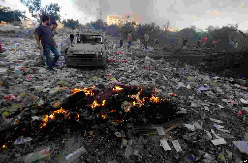 Palestinians look at a damaged vehicle amid debris in an area hit by an Israeli airstrike in Gaza City, July 24, 2014.