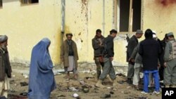 Afghans stand at the site of a suicide attack in Emam Saheb district of Kunduz province February 21, 2011