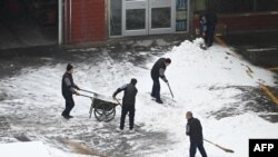 Workers clear snow from a courtyard after an overnight snowfall in Beijing on Dec. 11, 2023.