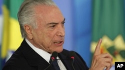 FILE - Brazil's President Michel Temer speaks during a ceremony at the Planalto Presidential Palace, in Brasilia, June 26, 2017. Temer is expressing defiance in the face of possible corruption charges.