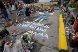 A woman kneels to weep at the spot where George Floyd was killed, as people gather during the sentencing hearing of former Minneapolis police officer Derek Chauvin for Floyd's murder, in Minneapolis, June 25, 2021.