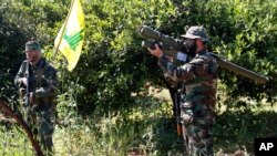 FILE - A Hezbollah fighter holds an Iranian-made anti-aircraft missile, right, as he takes his position with his comrade between orange trees, at the coastal border town of Naqoura, south Lebanon, April 20, 2017.