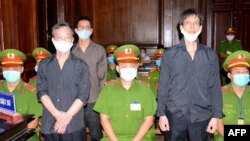 FILE - A photo released by the Vietnam News Agency on Jan. 5, 2021, shows VOA contributor Pham Chi Dung, right, with RFA contributor Nguyen Tuong Thuy, left, and Le Huu Minh Tuan at their trial in Ho Chi Minh City. A U.N. working group says Vietnam is arbitrarily detaining Pham.
