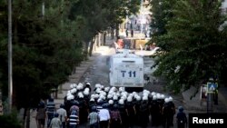 Kurdish protesters throw stones as they clash with riot police (foreground) in Diyarbakir, Turkey, Oct. 8, 2014.