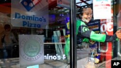 A man leaves as 'halal' logo of Indonesian Ulema Council is displayed on the facade of a restaurant in Jakarta, Indonesia, Wednesday, Nov. 11, 2020. As companies race to develop a COVID-19 vaccine and countries scramble to secure doses, questions…