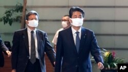 Perdana Menteri Jepang Shinzo Abe, kanan, berjalan di kantor perdana menteri di Tokyo Jumat, 28 Agustus 2020. Perdana menteri terlama Jepang Abe bermaksud meninggalkan jabatannya karena kesehatan yang menurun, menurut partai politiknya. (Foto: AP)