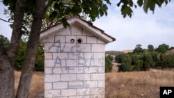 Tanda darurat di kapel Ortodoks Yunani menunjukkan jalan ke Albania, dekat desa Ieropigi, Yunani utara, di perbatasan Yunani-Albania, 28 September 2021. (AP Photo/Giannis Papanikos)