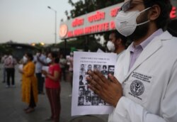 Para dokter memberi penghormatak kepada tentara India yang tewas dalam kontak senjata dengan tentara China di wilayah Ladakh, sambil memegang foto mereka, di New Delhi, India,18 Juni 2020.