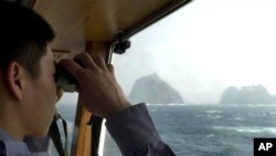 一名韩国海岸警卫队员在韩国东海的巡逻舰上用望远镜观察“独岛”（日本称之为“竹岛”）（2005年4月28日照片）