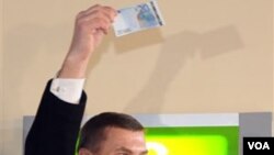 Perdana Menteri Estonia Andrus Ansip mengambil uang 20 Euro dari sebuah ATM di Tallinn, 1 Januari 2011.