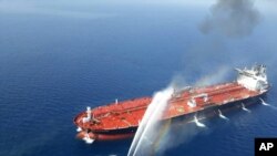 An Iranian navy boat sprays water to extinguish a fire on an oil tanker in the sea of Oman, Thursday, June 13, 2019.