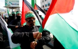 FILE - Masked Hamas militants wave their national flags during a protest in Gaza City, Feb. 21, 2020. Hamas on April 29, 2021, criticized the postponement of Palestinian legislative elections.