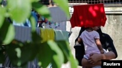 A Rohingya child bride who ran away from her husband carries her sister outside a shack she shares with her mother and siblings, on the outskirts of Kuala Lumpur, Malaysia, Feb. 9, 2017.