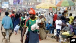 FILE - A man wearing a Cameroon soccer jersey walk past a busy Mokolo Market in Yaounde, Cameroon.