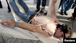 FILE - A Syrian opposition member of government shows what they say is one of the torture methods used in Syrian prisons during a demonstration in Beirut calling for more human rights in Syria, Dec. 10, 2009. 