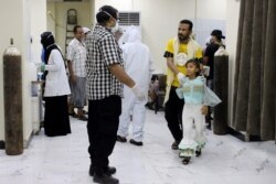 FILE - Yemeni medical workers wearing masks and protective gear talk to patients at hospital in Aden, Yemen, May 12, 2020.