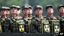 FILE - North Korean soldiers, carrying packs marked with a nuclear symbol, turn and look toward leader Kim Jong Un as they parade during a ceremony marking the 60th anniversary of the Korean War armistice in Pyongyang, North Korea, July 27, 2013. The U.S.
