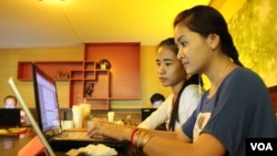 University students from the Royal University of Phnom Penh check the Internet in a coffee shop along the city's Russian Federation Boulevard, June 13, 2014. 