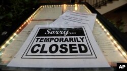 FILE - In this April 28, 2020 file photo, a closed sign is posted at a restaurant along the River Walk in San Antonio, Texas. 